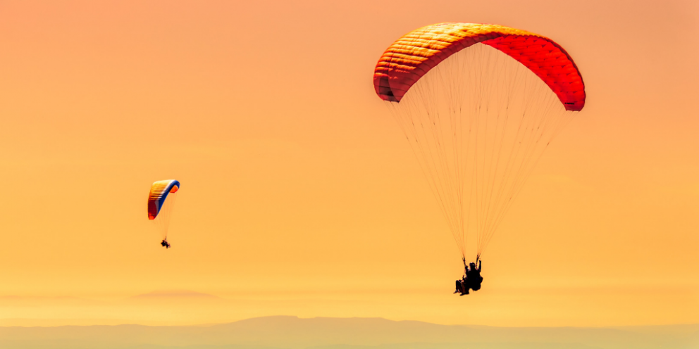 Two paragliders in sunlight