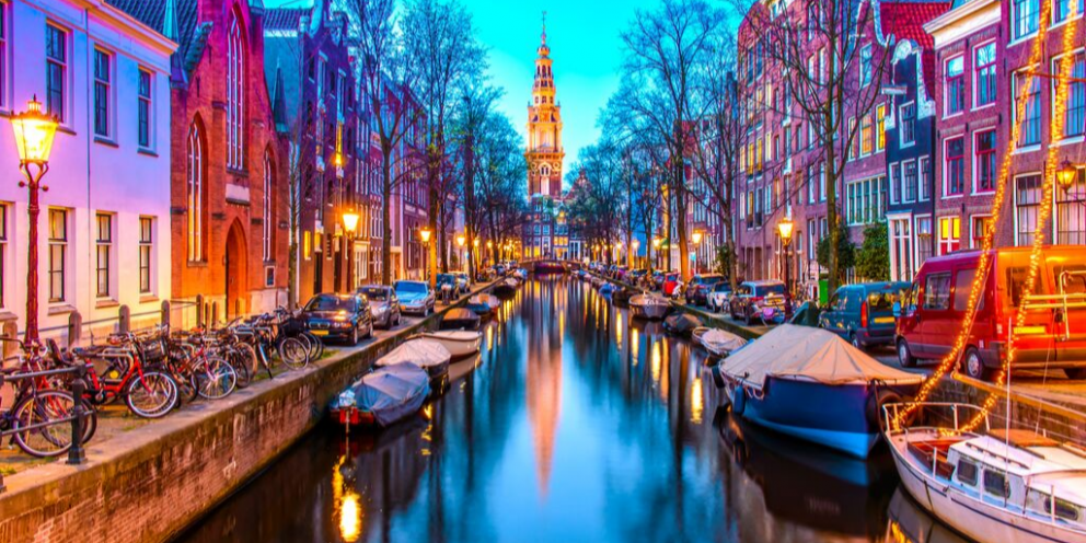 Picturesque Amsterdam in colorful lights with bikes, canal & cathedral