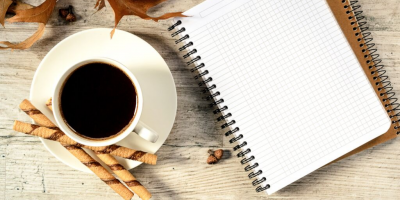 Coffee mug with wafers & open notebook on an autumn-flavored desk