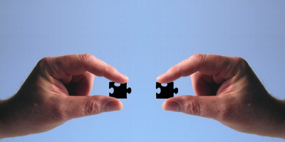 Two hands holding puzzle pieces that fit