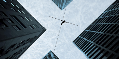 Acrobat balancing on a rope between tall buildings