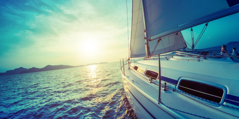 Boat sailing towards sunny horizon