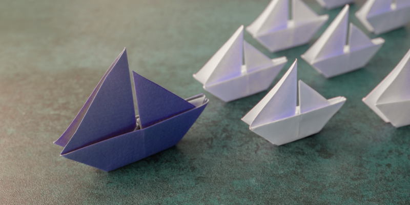Paper ships following bigger leading paper ship