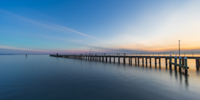 Long pier extending over sea during sunset