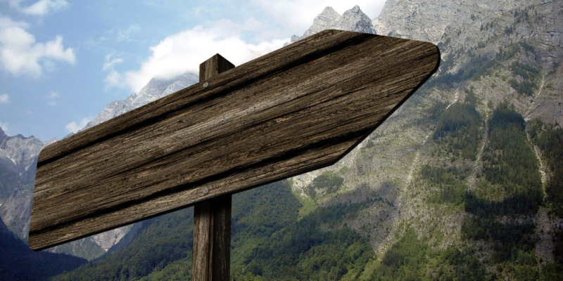 Wooden signpost in a mountainous area pointing to the right